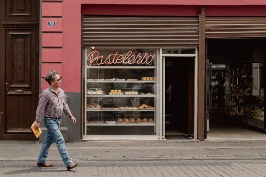 founder walking near candidate storefront and checking pedestrian flow with printed lease checklist