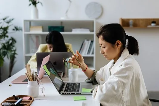 HR manager checking remaining training support balance on laptop with employee education calendar and receipts | 직원교육 잔여 한도와 교육 일정을 함께 확인하는 장면