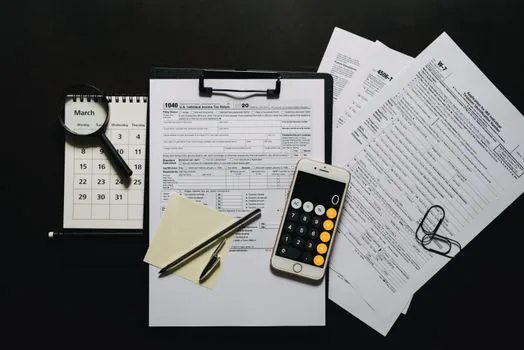 Korean business owner marking June deadline on tax calendar beside income tax filing documents and bank app
