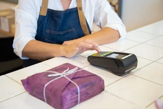 Korean cafe owner checking card terminal receipt and merchant sales statement beside laptop, realistic small business counter photo | 카드단말기 영수증과 가맹점 매출 내역을 함께 확인하는 장면