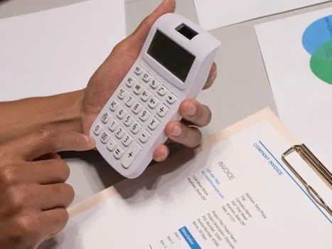 Korean ecommerce seller downloading VAT report from laptop, calculator, invoice folder, and order printouts on bright office desk, realistic photo, no readable private data | 스마트스토어 부가세 신고내역 파일을 내려받는 장면