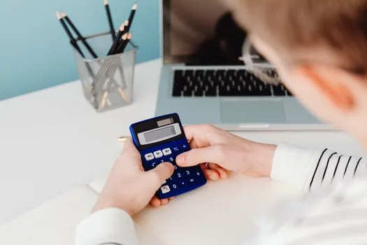 Korean prospective franchise owner comparing disclosure document search results and brand list on laptop, notebook and calculator on desk, realistic office photo | 가맹사업 정보공개서 검색 결과를 비교하는 모습