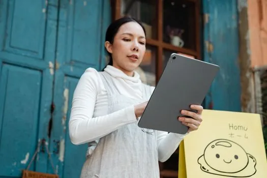 Korean restaurant owner checking food delivery platform request status, business license copy, bank account document and store name checklist on laptop, realistic photo, no readable private data | 배달앱 사업자정보 변경 뒤 요청처리와 정산계좌 서류를 확인하는 장면