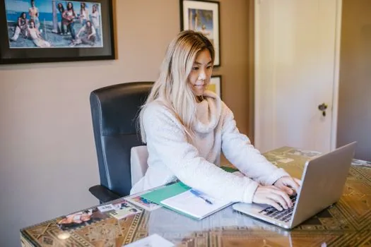 Korean small business owner completing online education course on laptop with certificate checklist