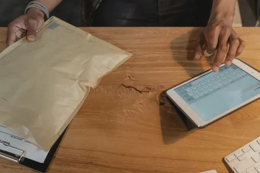 Korean small business owner matching DM orders with bank transfer spreadsheet and parcel invoices, realistic desk scene