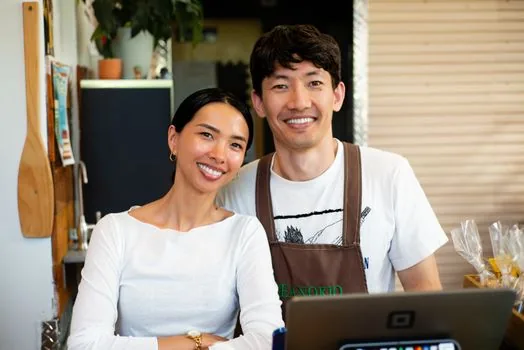 Korean small cafe owner comparing air conditioner quote, energy efficiency label and support checklist on counter, realistic bright shop photo | 소상공인 대표가 냉난방기 견적서와 1등급 라벨 조건을 확인하는 장면