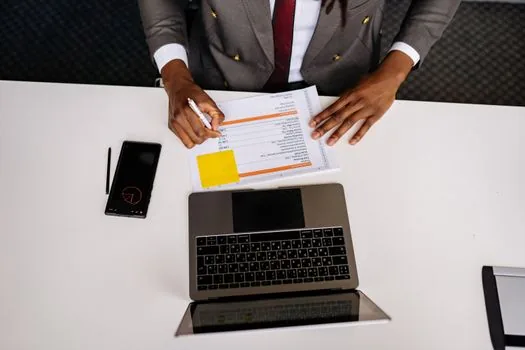 Korean startup CEO reviewing shareholder list, articles of incorporation and beneficial owner checklist on laptop, bright document desk | 주주명부와 실제소유자 확인 자료를 정리하는 장면