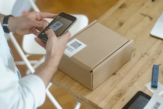 Return shipping fee memo beside parcel box and online store refund policy page on laptop, realistic bright shop office | 교환·반품비와 환불 조건을 상세페이지 문구로 정리하는 장면