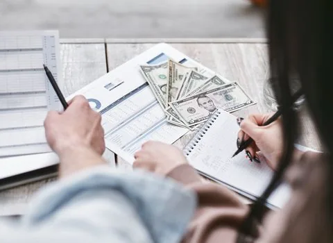 small business owner comparing income amount certificate, sales report and calculator on bright desk, realistic document photo | 수입금액과 소득금액을 나눠 확인하는 세무 서류 대조 장면