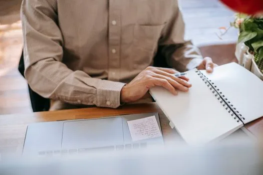 small business owner comparing monthly AI tool spend spreadsheet with team workflow notes on laptop