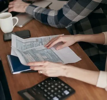 Small business owner organizing appliance receipt, business certificate and bank account document before online support application, bright office desk photo | 지원금 신청 전 구매증빙과 사업자 서류를 정리하는 장면